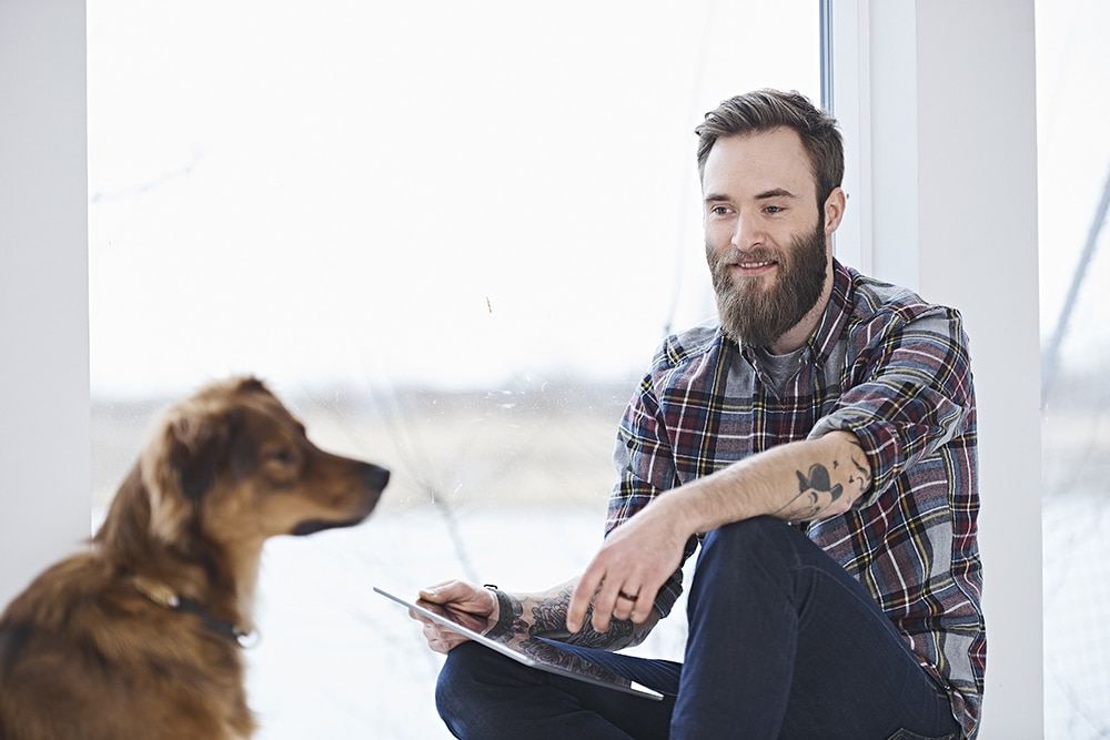 Young male designer with dog in design studio window seat