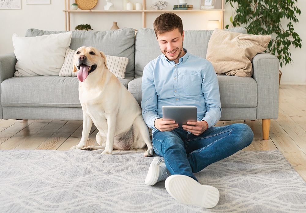 Young man at home with a tablet and dog
